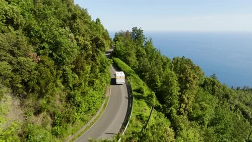 Aerial view following a camper driving on a high altitude road in Liguria, Italy