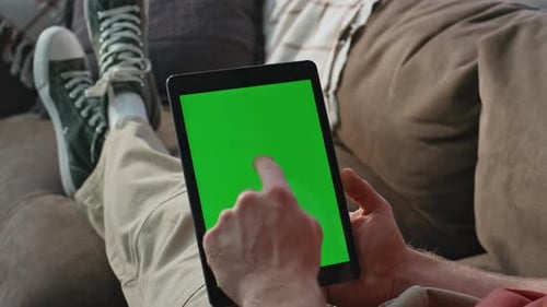 Man Relaxes on Couch Using Tablet With Green Screen