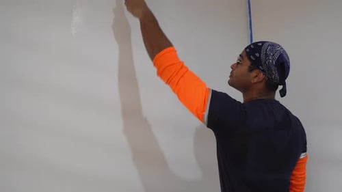 Man Using Roller To Paint White Color On The Wall - Close Up