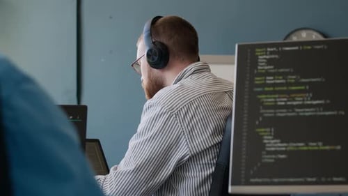 Bearded Man Putting on Headphones at Work