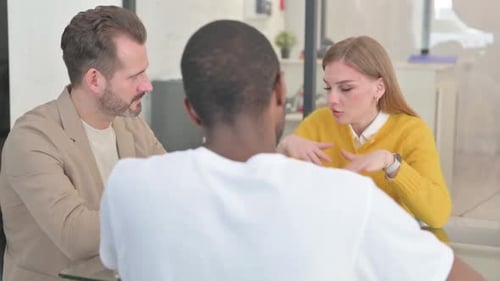 Three People Meeting Around a Conference Table