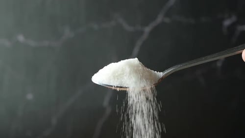 Slow Motion of White Sugar Pouring From a Spoon