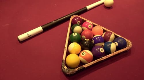 Old billiard balls, cue and triangle on red carpet
