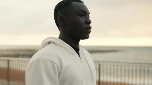 Side view of young man walking by the sea on the promenade