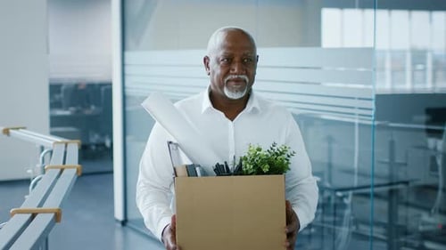 Homme d'affaires afro-américain transporte des fournitures de bureau dans un cadre d'entreprise