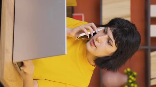 Woman Talking on Phone While Using Laptop