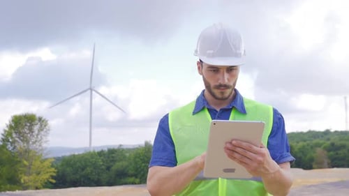 Engineer Uses Tablet Near Wind Turbine, Gives Thumbs Up