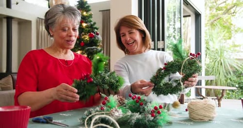Women Crafting Christmas Wreaths Together at Home