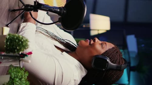 Woman Speaks Into Microphone Wearing Headphones at Desk