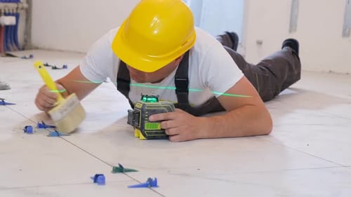 Construction Worker Lays Tile Using Laser Leveling Tool