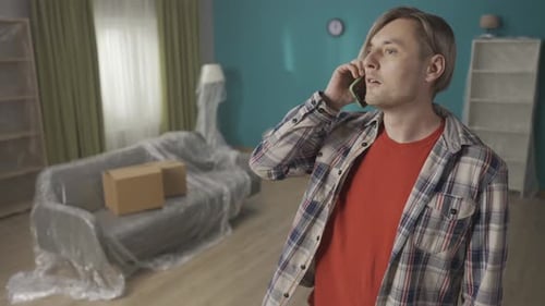 The Man Standing in the Living Room Swears on the Phone Portrait of a Blonde Man Emotionally Talking