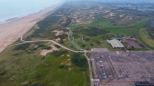 A stunning aerial view of a coastal landscape featuring sandy beaches, grassy dunes winding pathways