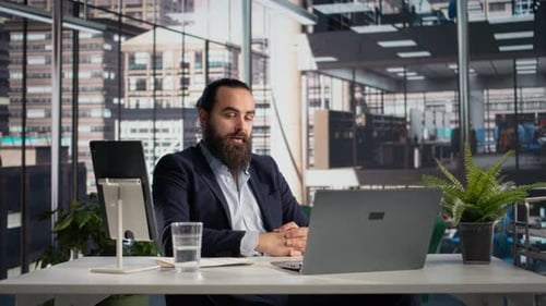 Bearded Man Attends Virtual Meeting in Modern Office