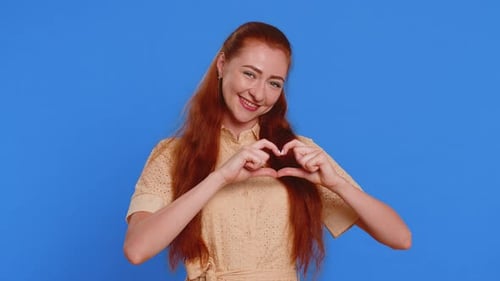 Woman Making Heart Shape With Hands on Blue