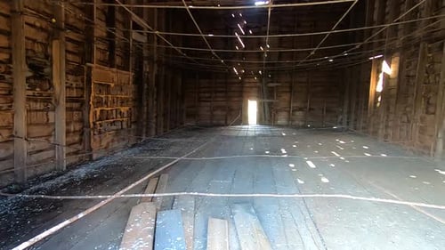 Dentro de un viejo y sucio granero abandonado con vigas que cuelgan de las paredes y la luz viaja a través de Sma