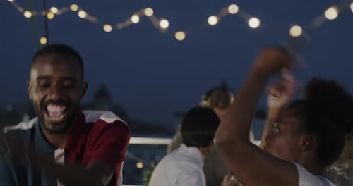 Friends Dancing and Celebrating on City Rooftop at Night