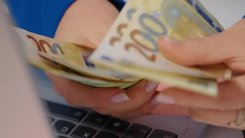 Foto portátil de perto das mãos de uma mulher caucasiana contando dinheiro.