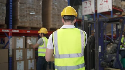 Blue collar workers are working at warehouse.