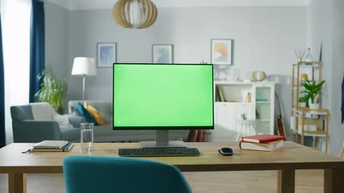 Modern Personal Computer with Mock-up Green Screen Display Standing on the Desk of the Cozy Home Of