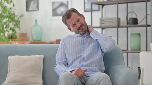 Man Rubs Stiff Neck in Living Room