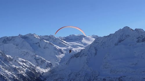 paragliding in a beautiful winter landscape. The sun is shining and the mountains are full of snow.