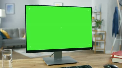 Modern Personal Computer with Mock-up Green Screen Display Standing on the Desk of the Cozy Home Of