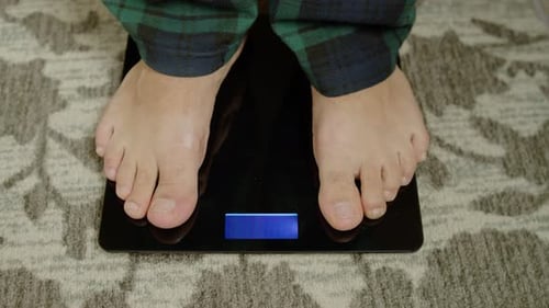 Feet Stepping onto a Black Digital Scale
