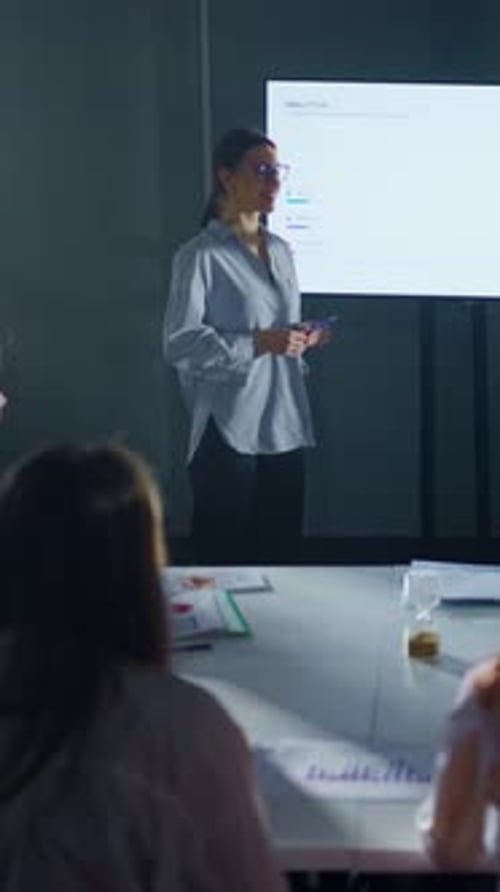 Confident Businesswoman Presenting Colorful Analytics Charts on Large Screen During Modern Office