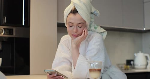 Woman in Robe Relaxing with Phone in Kitchen