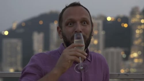 Man Smiling and Drinking Champagne Against City Skyline