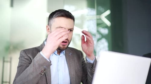 Frustrated stressed businessman reads bad news on a laptop sitting at workplace in business office.