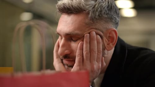 Man Looking Sad with Shopping Bags