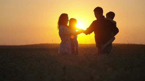 Family Silhouetted in Golden Field at Sunset