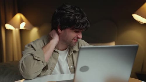 Man Massaging Neck While Using Laptop Computer