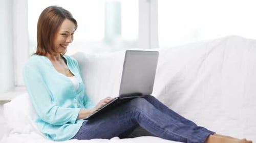 Woman Using Laptop While Relaxing on White Couch