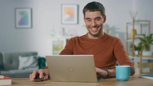 Smiling Man Working On Laptop At Wooden Desk