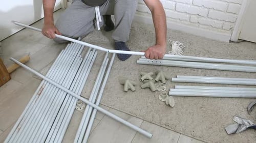 Um homem está montando uma barraca de jardim. Conecta tubos e adaptadores