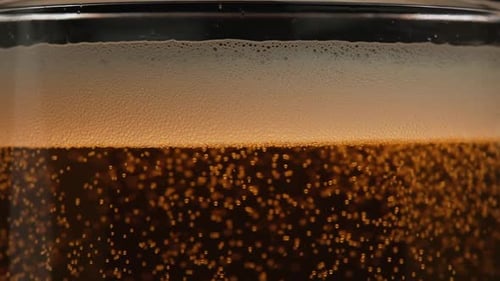 Bolhas em um copo de cerveja em câmera lenta. Uma caneca de cerveja dourada brilha na luz. As bolhas sobem