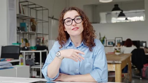 Young Woman Presenting to Camera in Modern Office