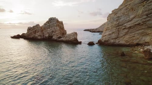 Sunset view of rocky cliffs and calm sea at a hidden bay on Kefalonia island in Greece