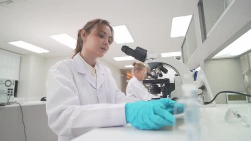 Woman in Lab Coat Using Microscope for Science