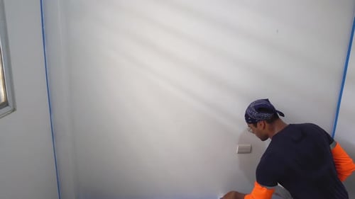 Person Painting Wall in Brightly Lit Room