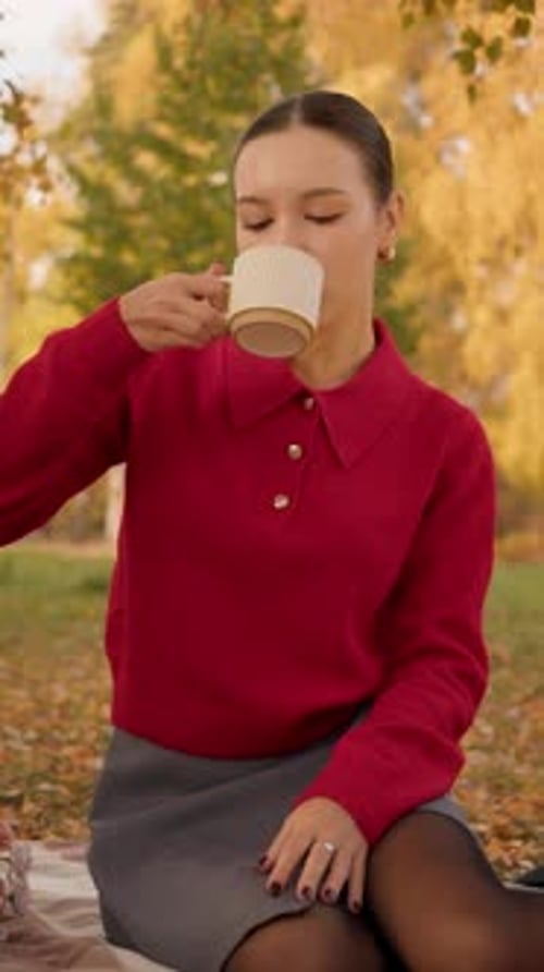 Young Woman Drinking Tea Outdoors in Autumn Setting