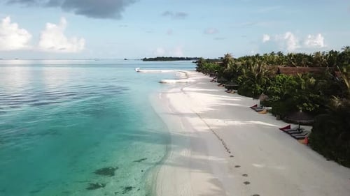 Drone voando sobre a costa marítima da Ilha das Maldivas, água azul, areia branca, palmeiras verdes e vilas. 4K