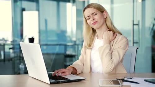 Woman at Computer Massages Stiff Neck in Office