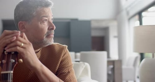 Man with Guitar Looks Thoughtful Indoors