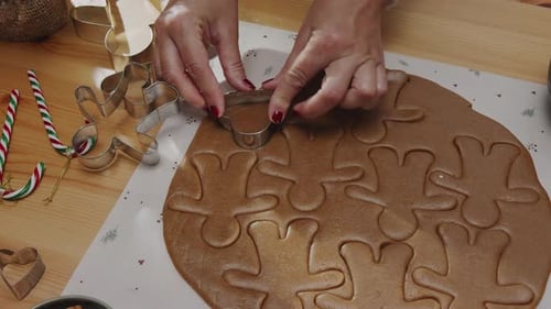 Hands Cutting Gingerbread Men for Christmas Baking
