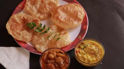 rotation Chole Bhature or Chick pea curry and Fried Puri served in terracotta crockery over back bac
