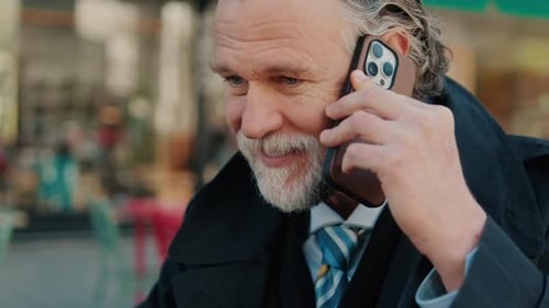 Smiling Businessman Talks On Phone At Cafe