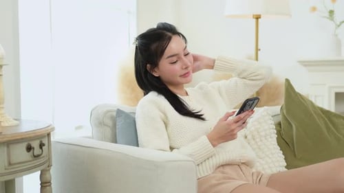 Woman Relaxing at Home Using Smartphone